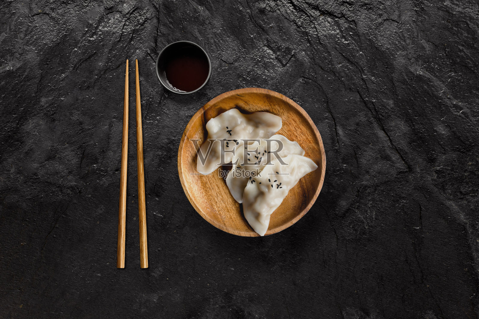在黑色石板上涂酱油的亚洲水饺。照片摄影图片