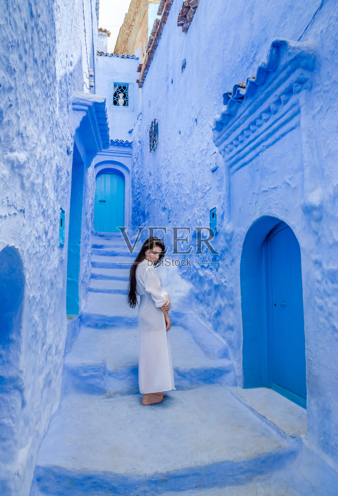 美丽的女孩穿着白色的裙子在蓝色城市舍夫沙万，摩洛哥照片摄影图片