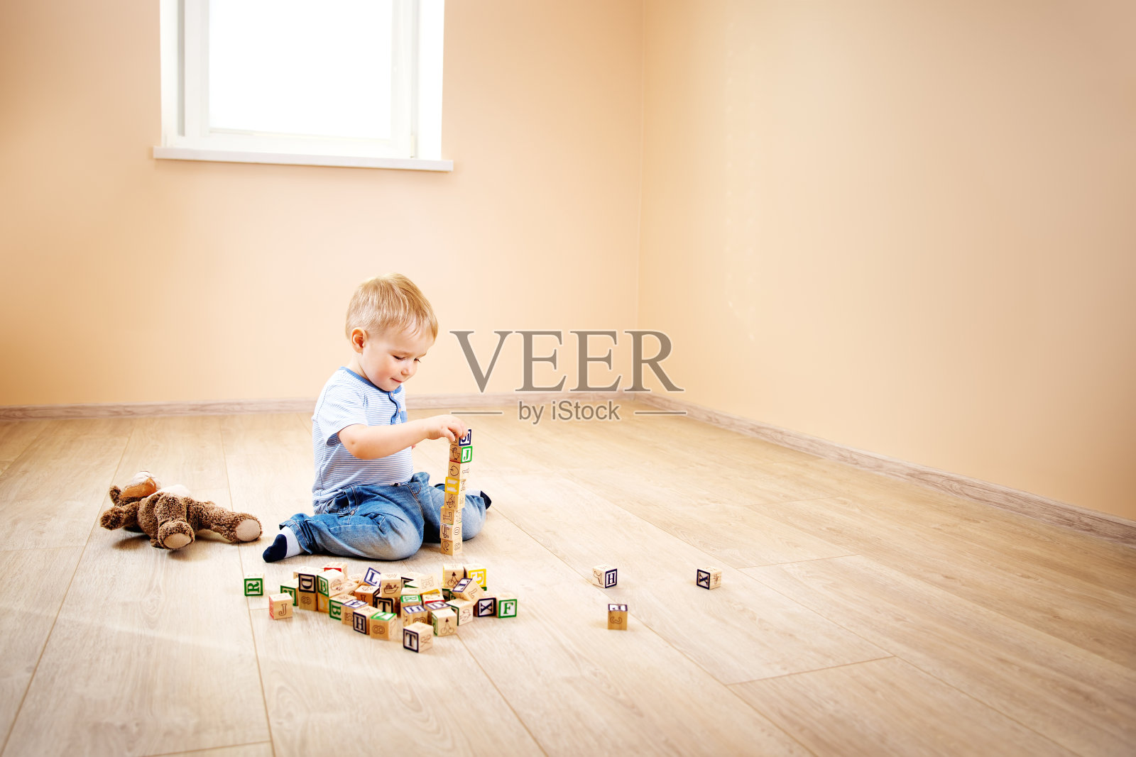 两岁的孩子坐在地板上和木块一起照片摄影图片
