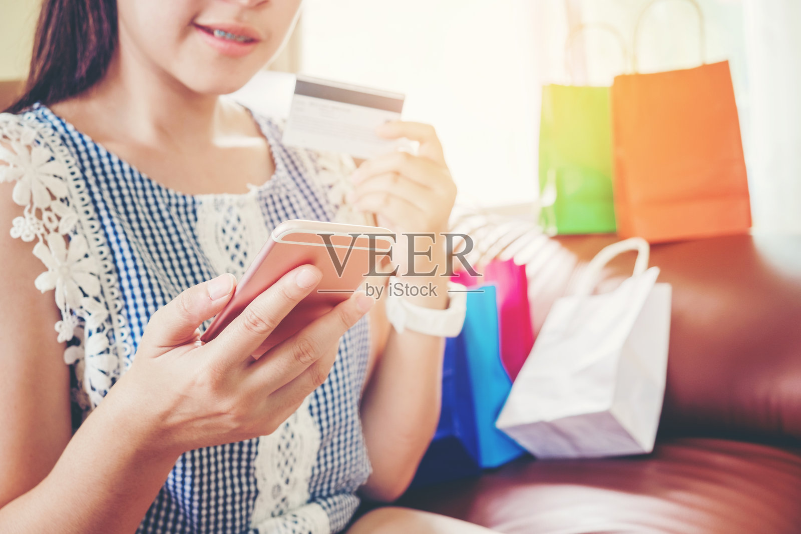 女人用智能手机在网上购物，用信用卡在家享受照片摄影图片