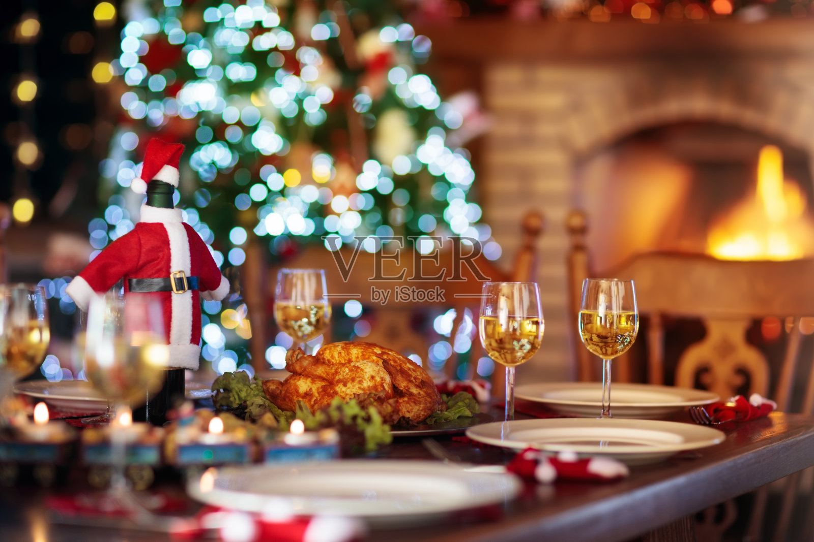 在壁炉和圣诞树旁吃圣诞晚餐。照片摄影图片