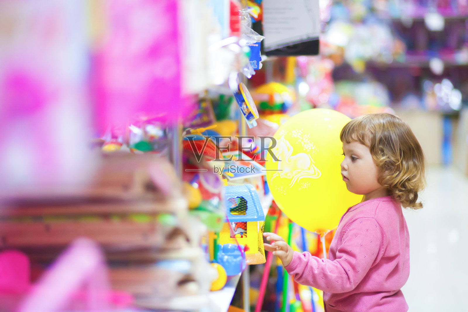 蹒跚学步的孩子在玩具店购物。照片摄影图片