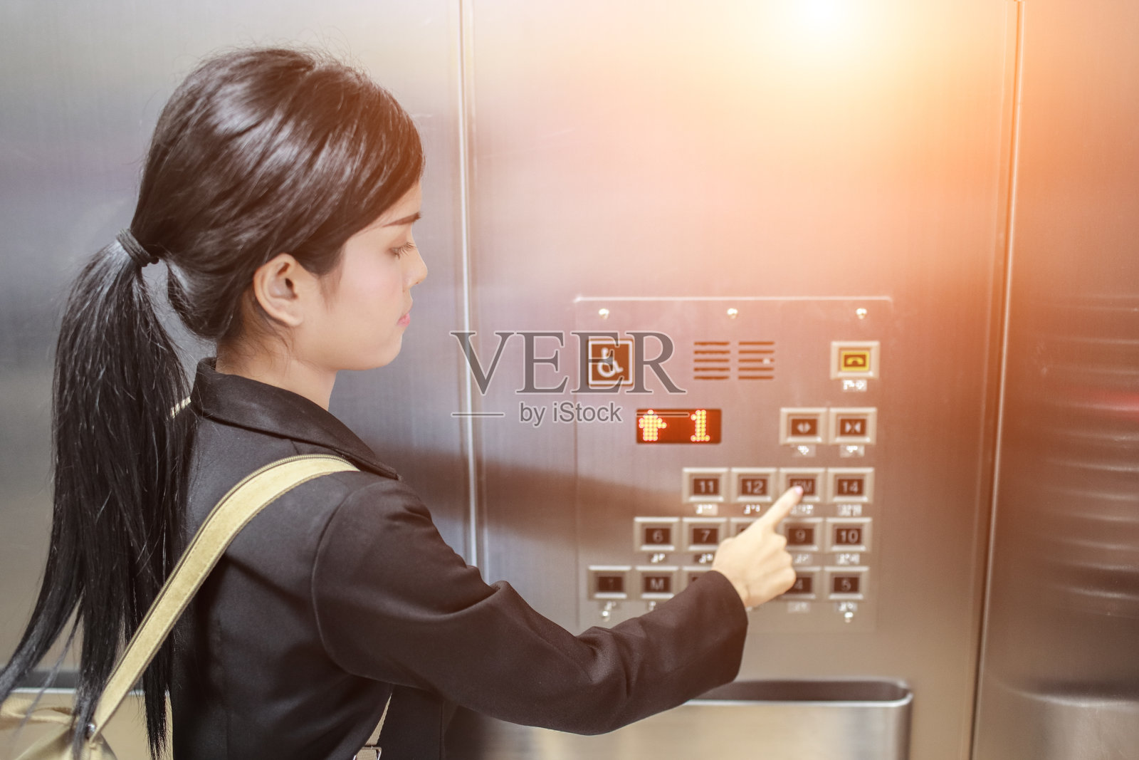 商务女性按电梯按钮具有阳光效果。女商人在电梯里。照片摄影图片