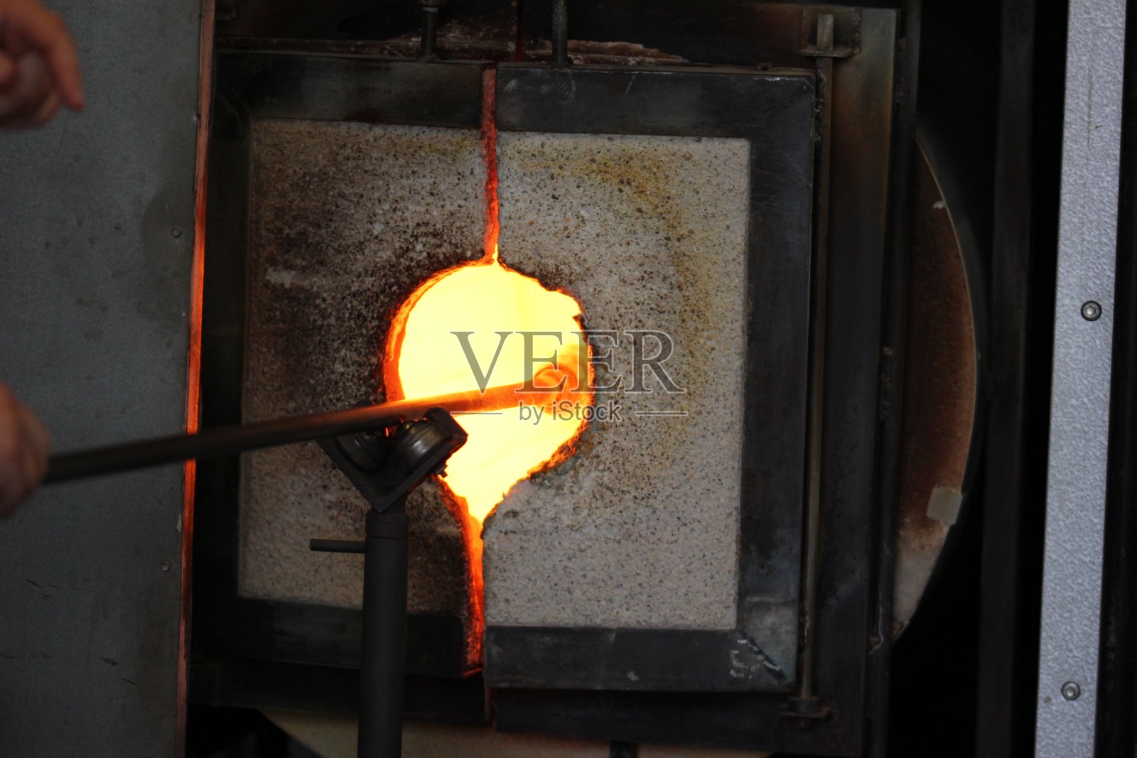 将玻璃熔在熔炉中的金属棒上用于吹制玻璃照片摄影图片