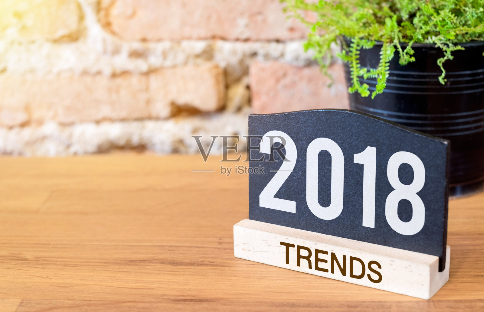 2018年新年趋势的黑板报和绿色植物的木桌在砖墙。明年的商业计划。照片摄影图片