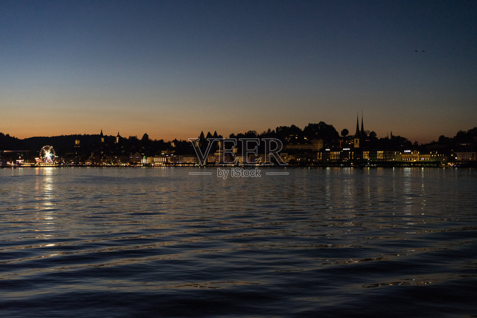 日落在卢塞恩湖从船与城市背景照片摄影图片
