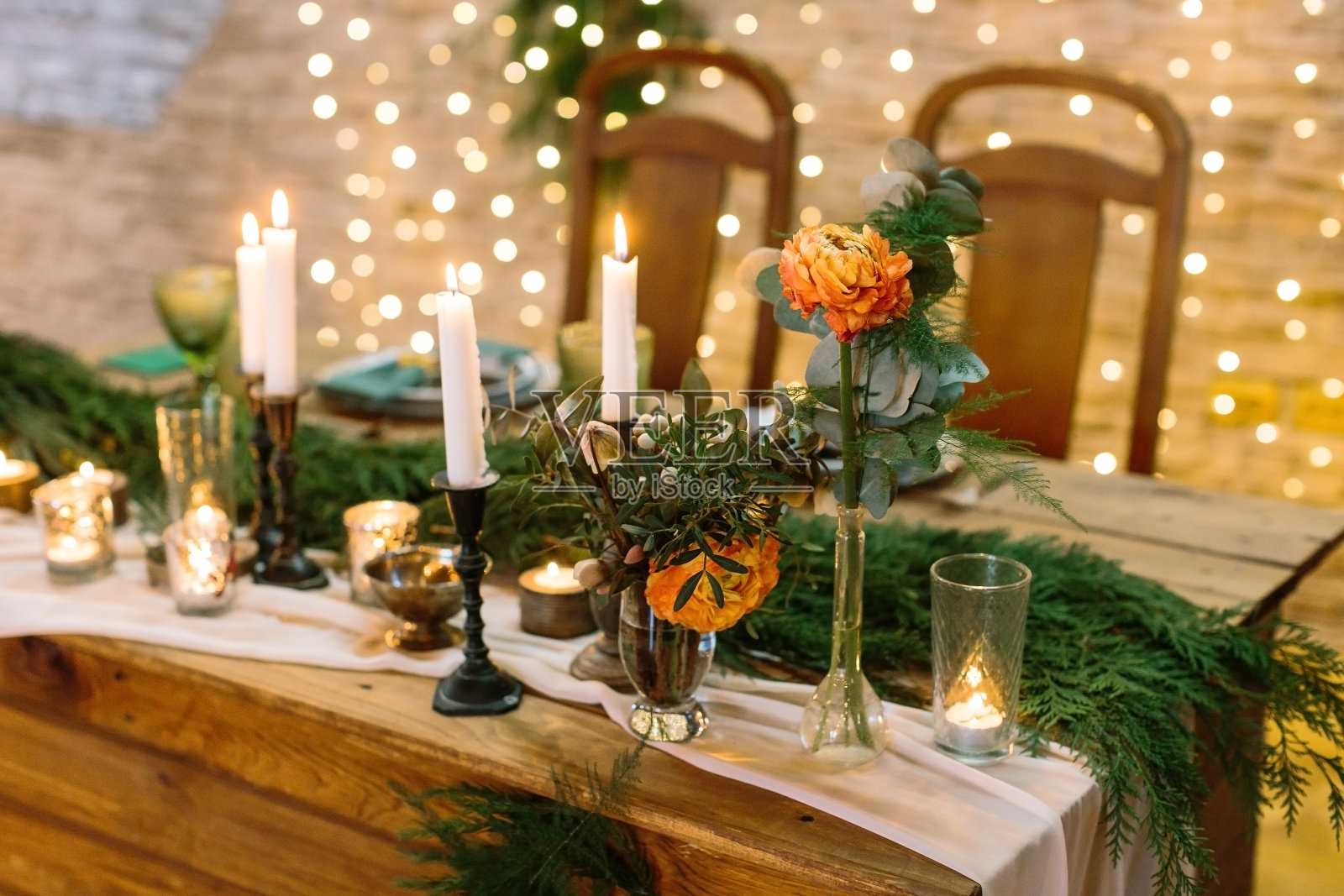 圣诞节，庆祝，设计理念。娇嫩的花朵，玫瑰花蕾呈鲜橙色，周围点缀着许多蜡烛、蜡烛腿、眼镜和云杉毛茸茸的枝干照片摄影图片