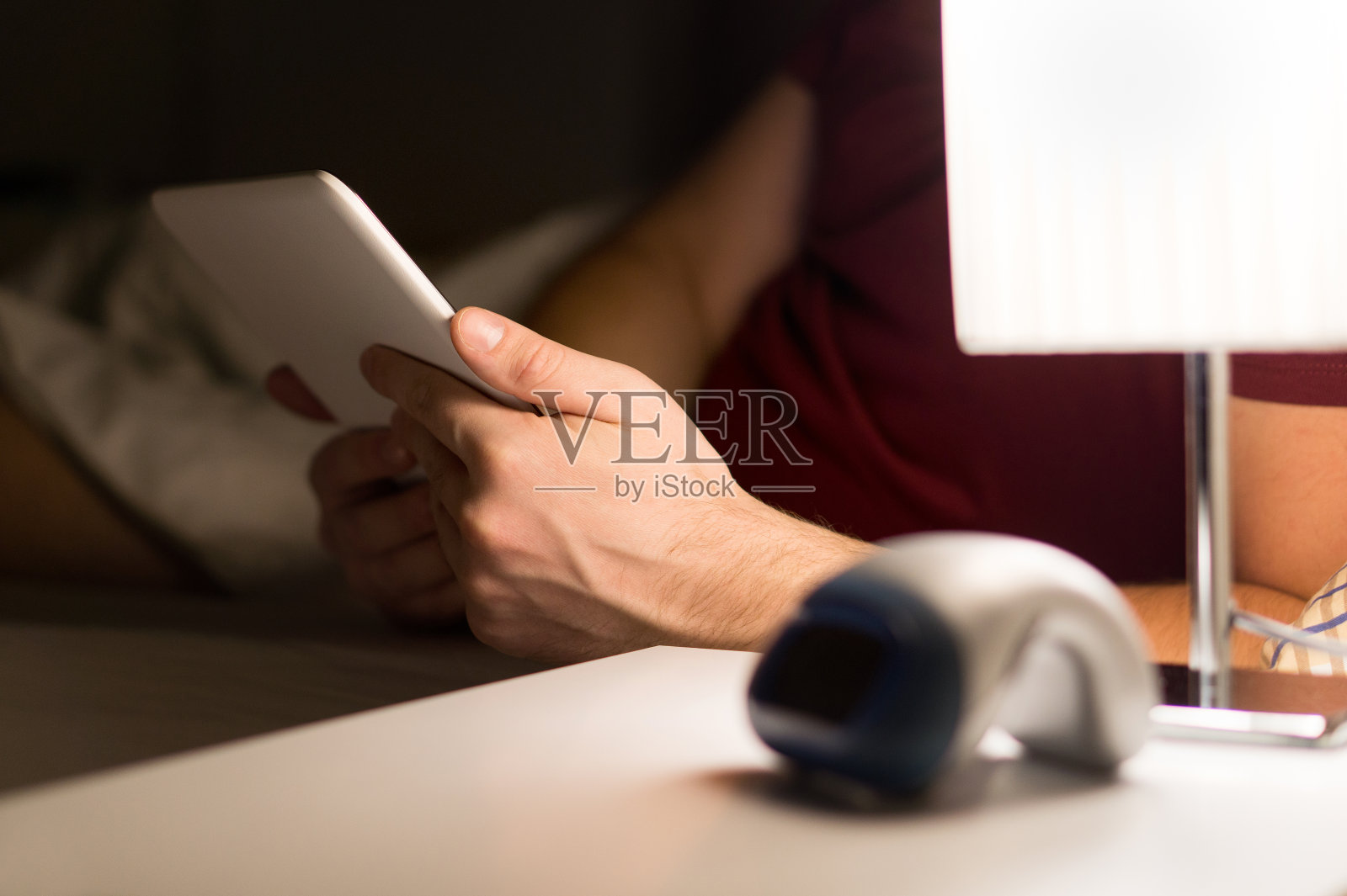 男人在床上看电子书或使用平板电脑。卧室里的现代移动设备。照片摄影图片