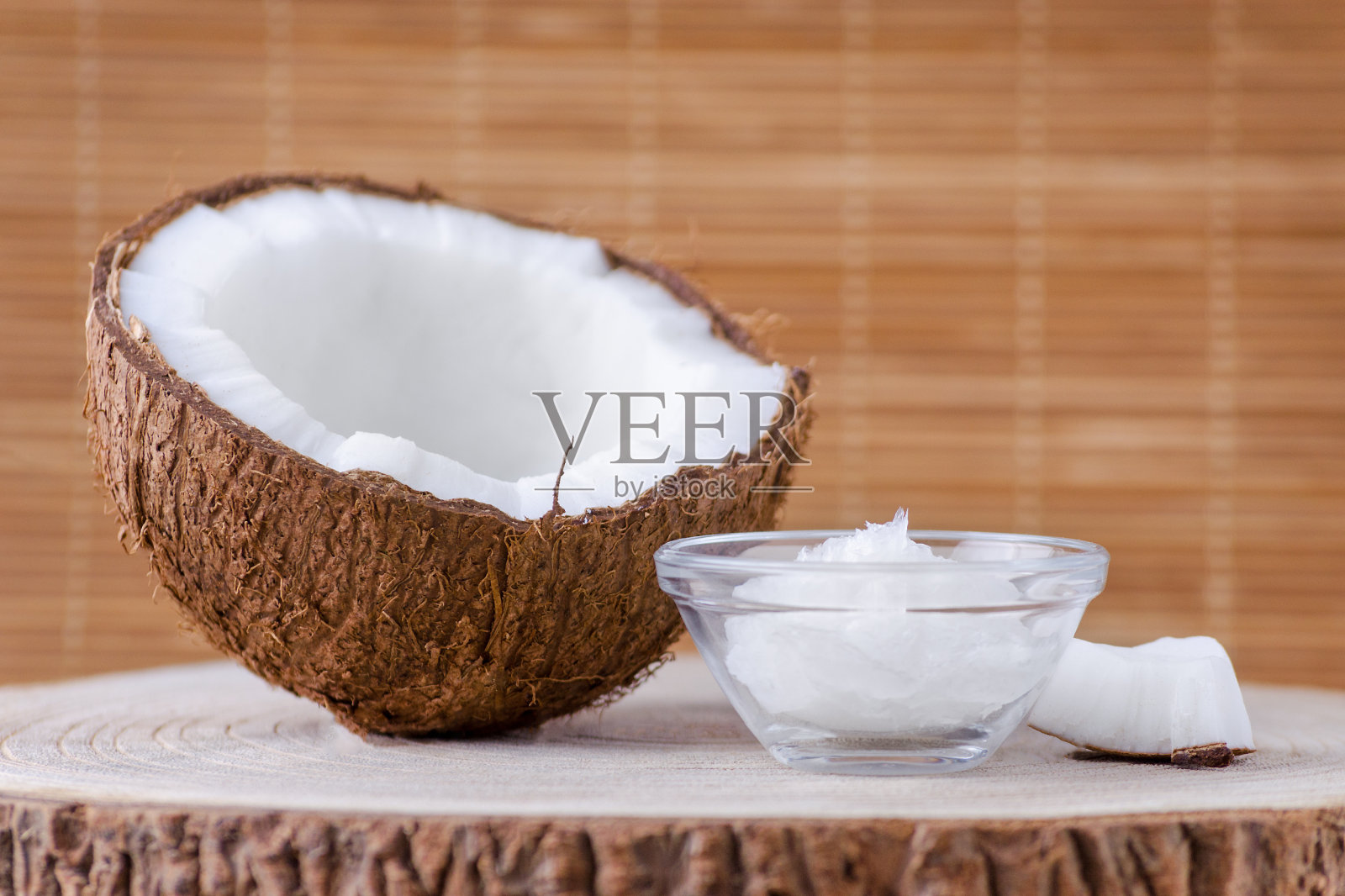 有机椰子油在玻璃碗和椰子在自然棕色背景照片摄影图片
