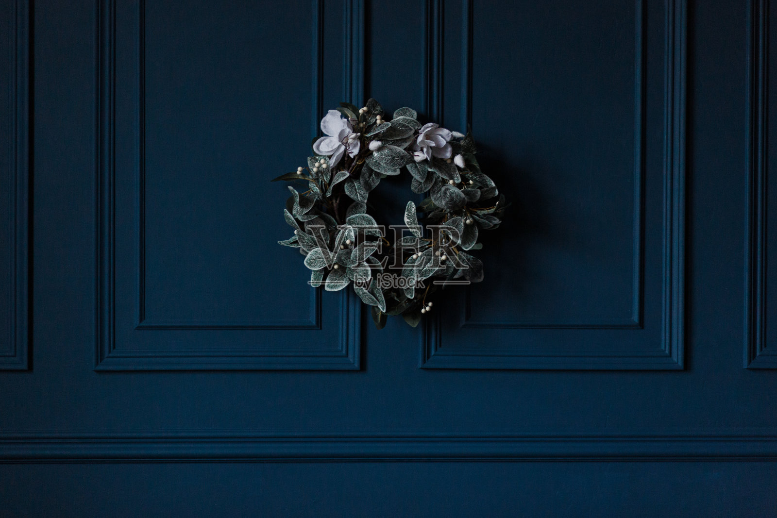传统的圣诞装饰常青树花环与白色的花丝带在深蓝色的墙壁背景照片摄影图片