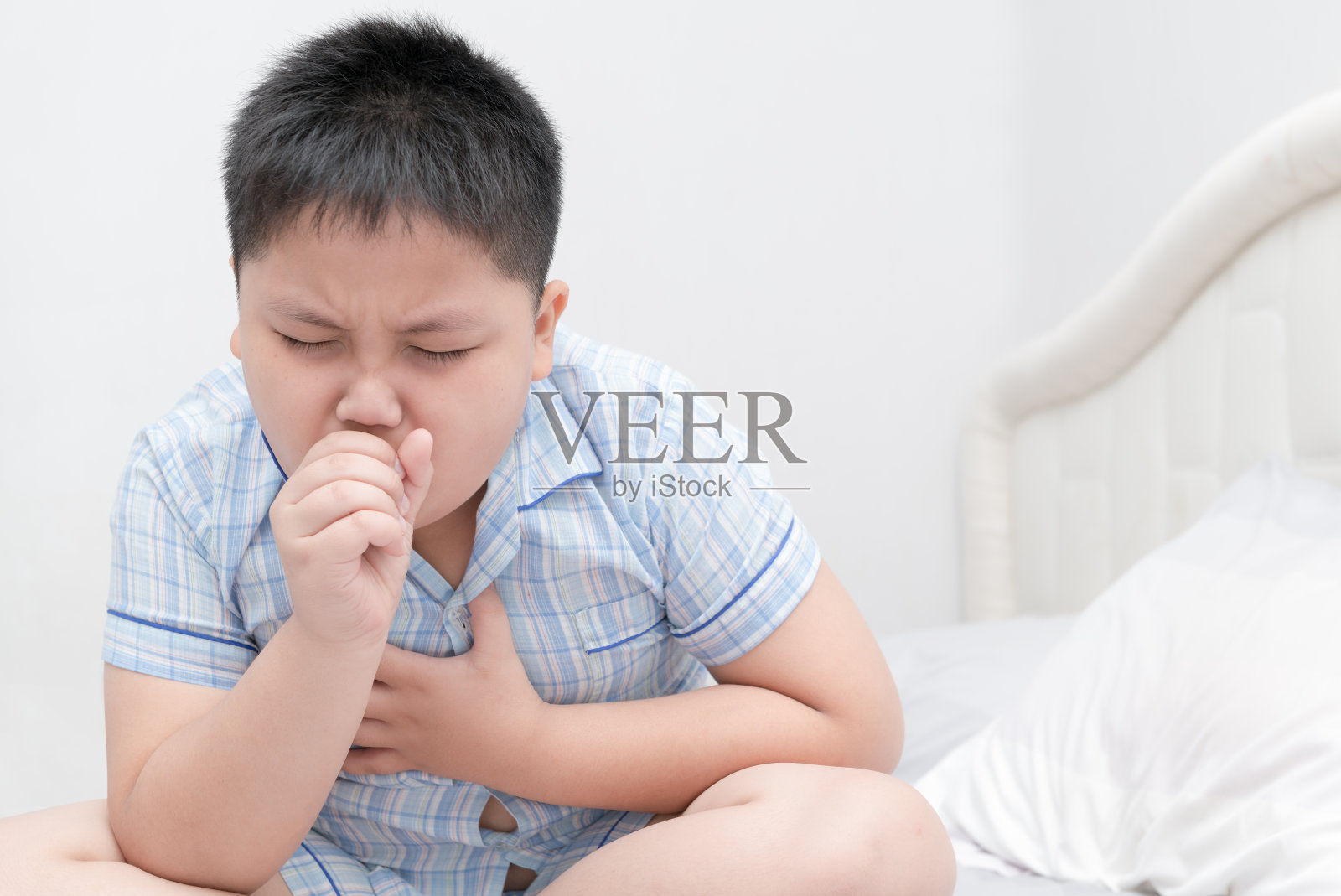 生病的肥胖男孩正在咳嗽和喉咙感染照片摄影图片
