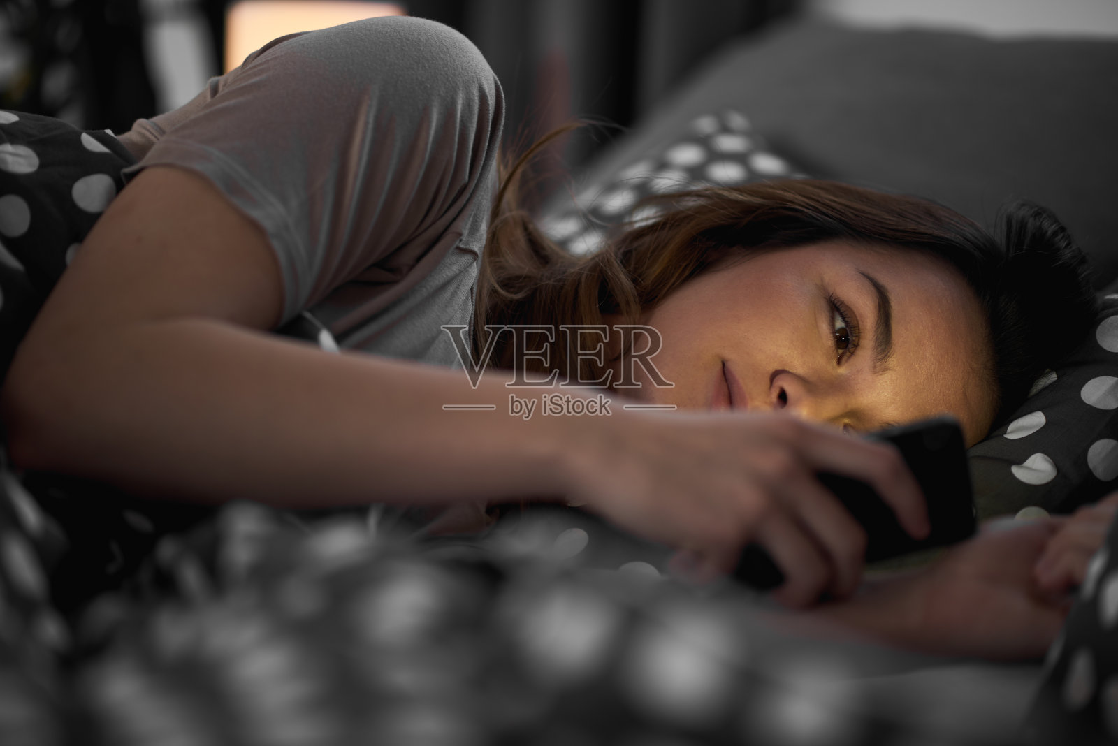 女孩躺在床上玩手机照片摄影图片