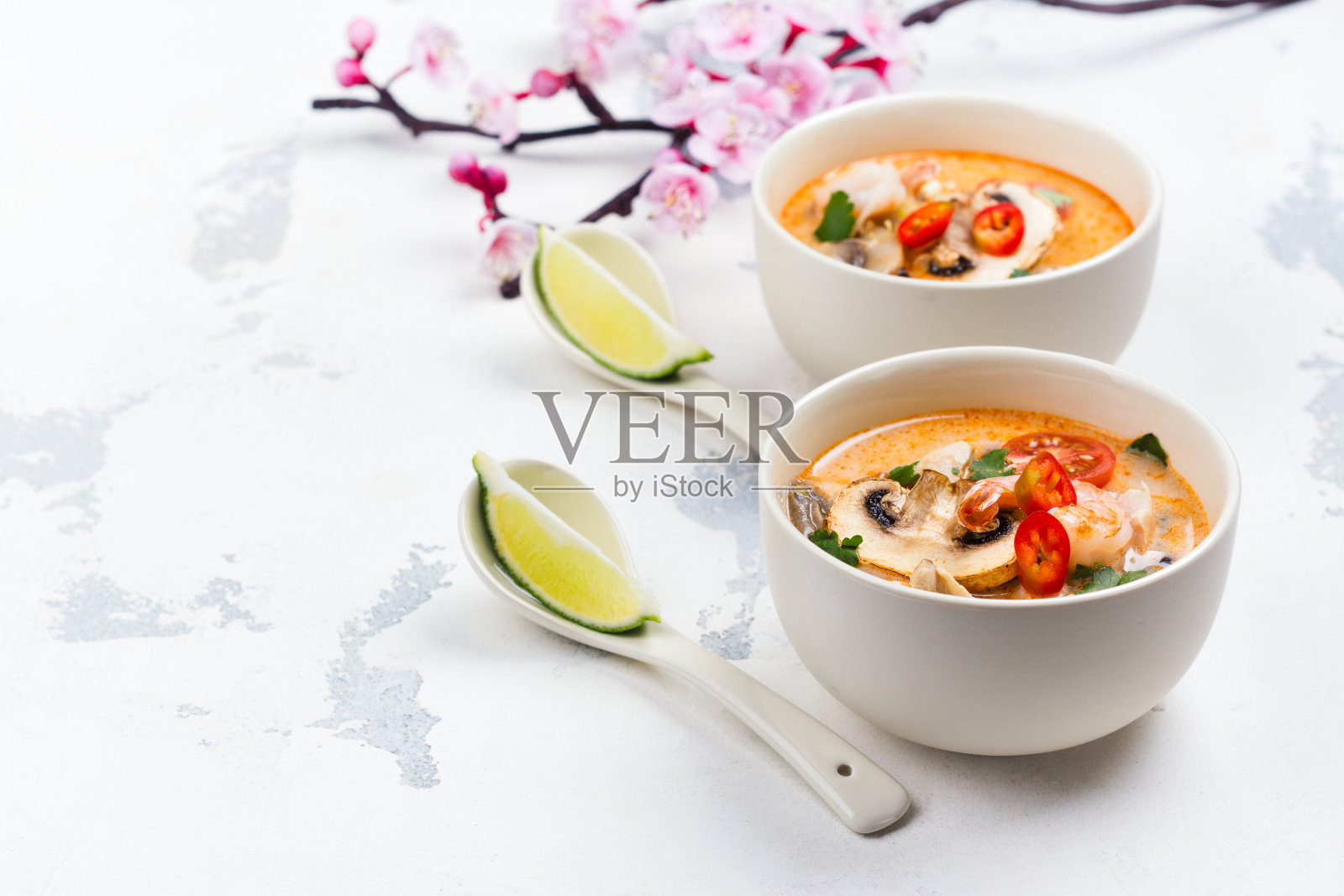 传统冬阴汤与盛开的樱花枝在白色的石头桌上照片摄影图片