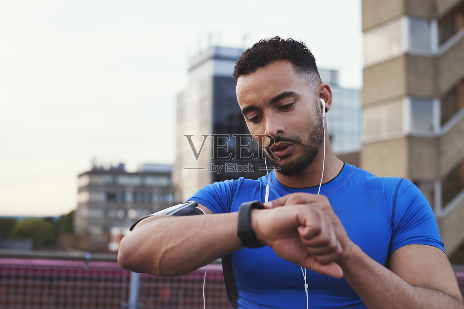 男性跑步者在城市街道上使用智能手表上的应用程序照片摄影图片
