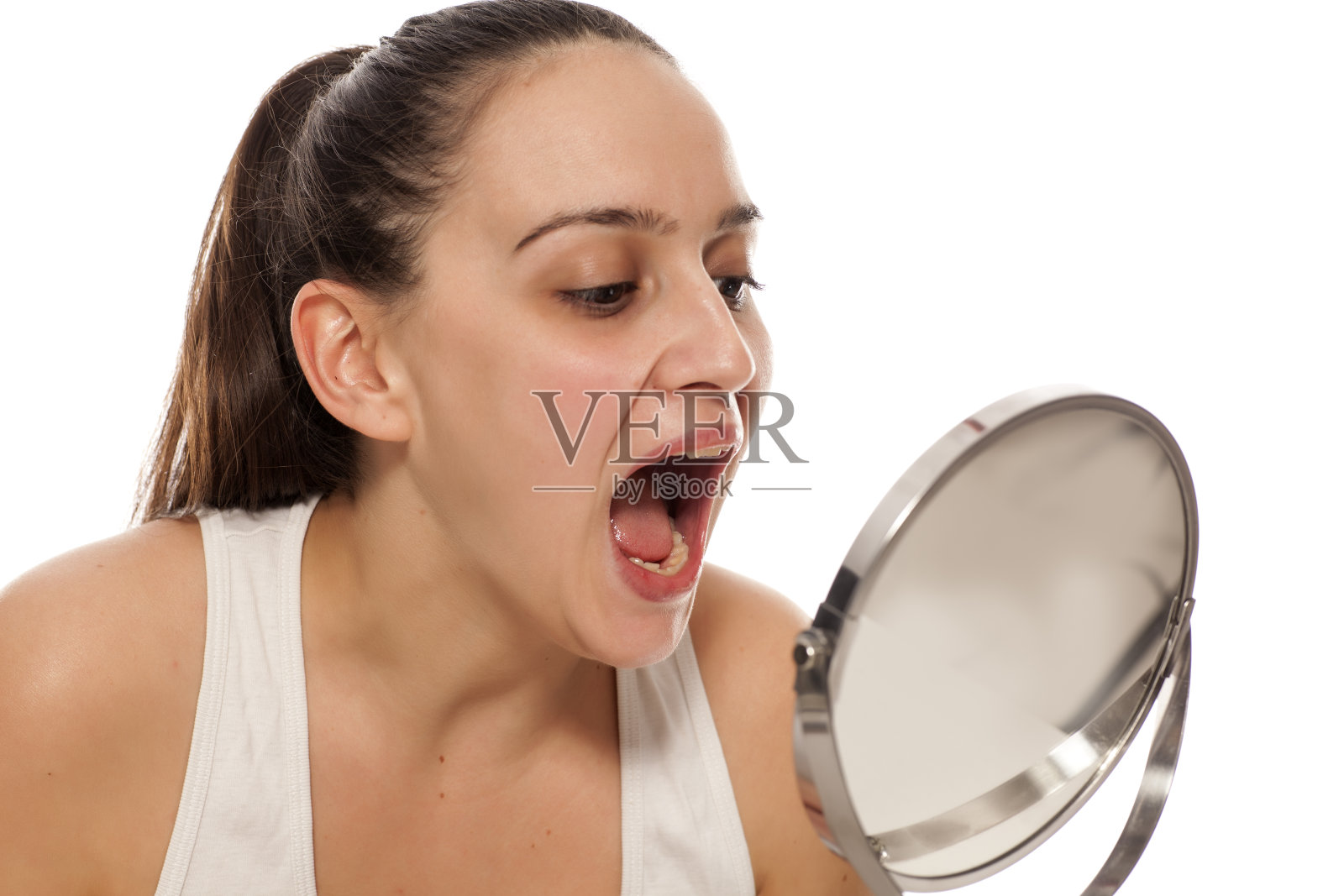 年轻女子对着镜子检查自己的嘴照片摄影图片