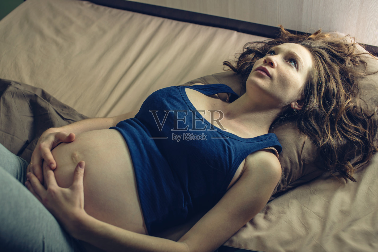 孕妇躺在床上感到肚子疼，晚上失眠。怀孕和健康的概念照片摄影图片