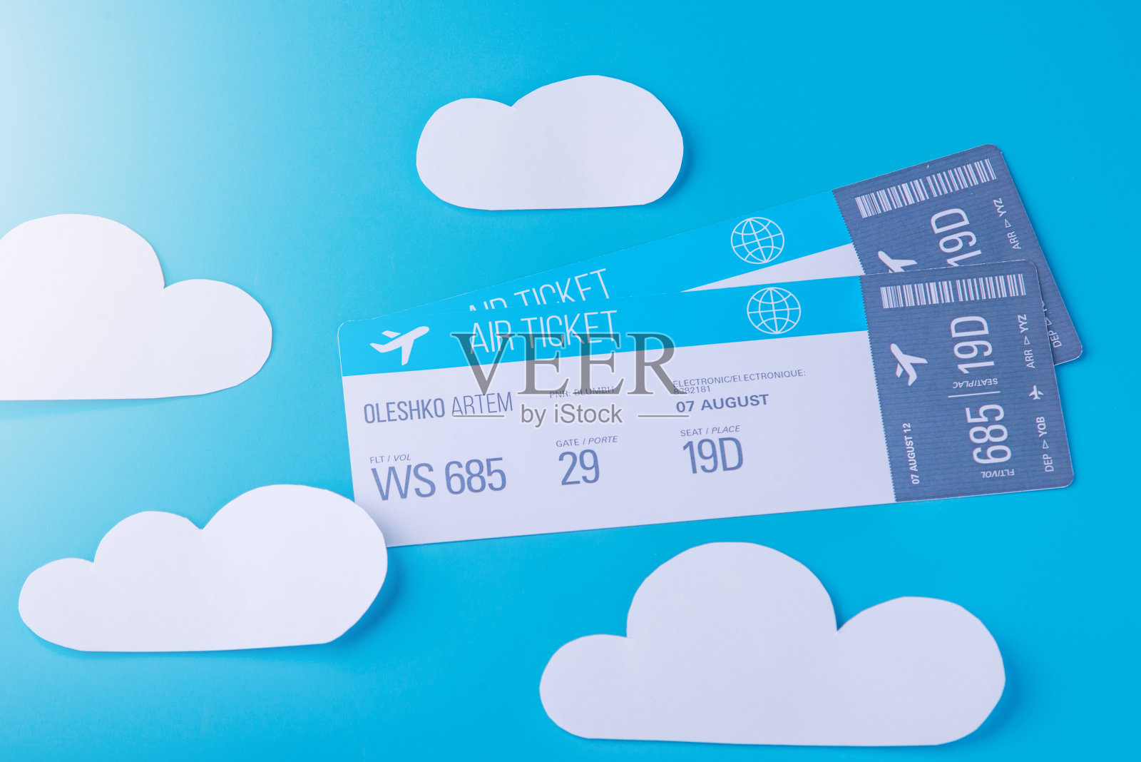 两张以蓝天为背景、纸云为背景的飞机机票。概念旅游和在线预订照片摄影图片