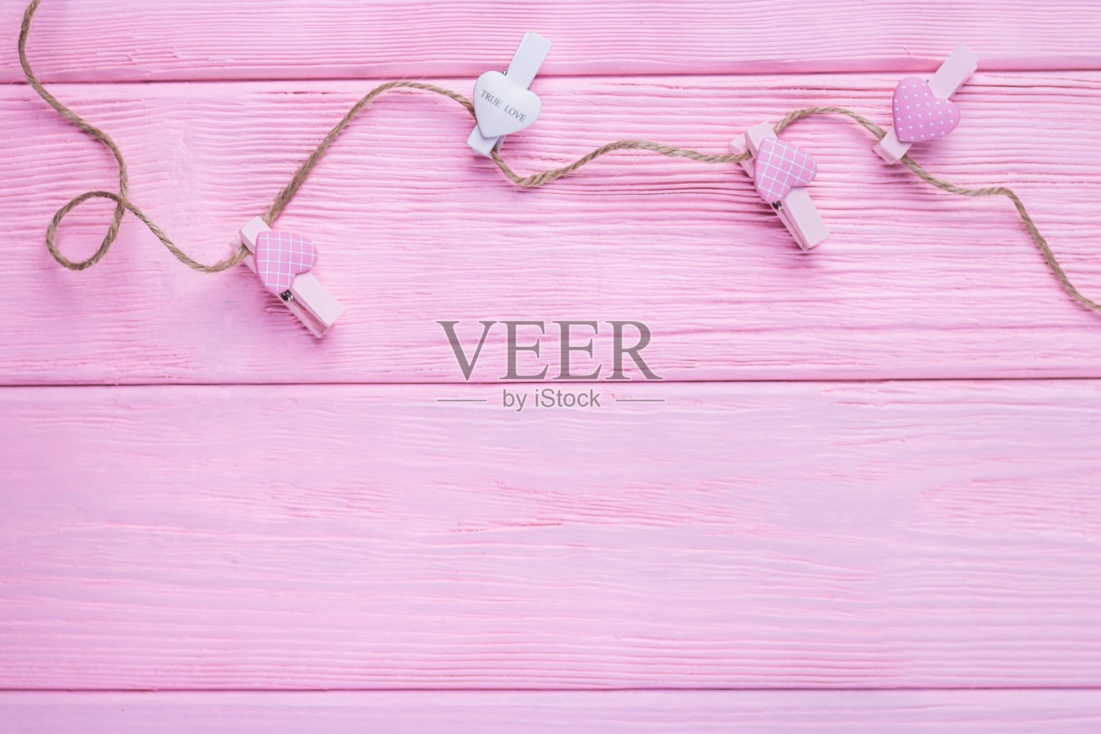 情人节快乐。情人节的背景。粉色和白色的心，晾衣绳上的晾衣夹在粉红色的背景上。俯视图，自由空间插画图片素材