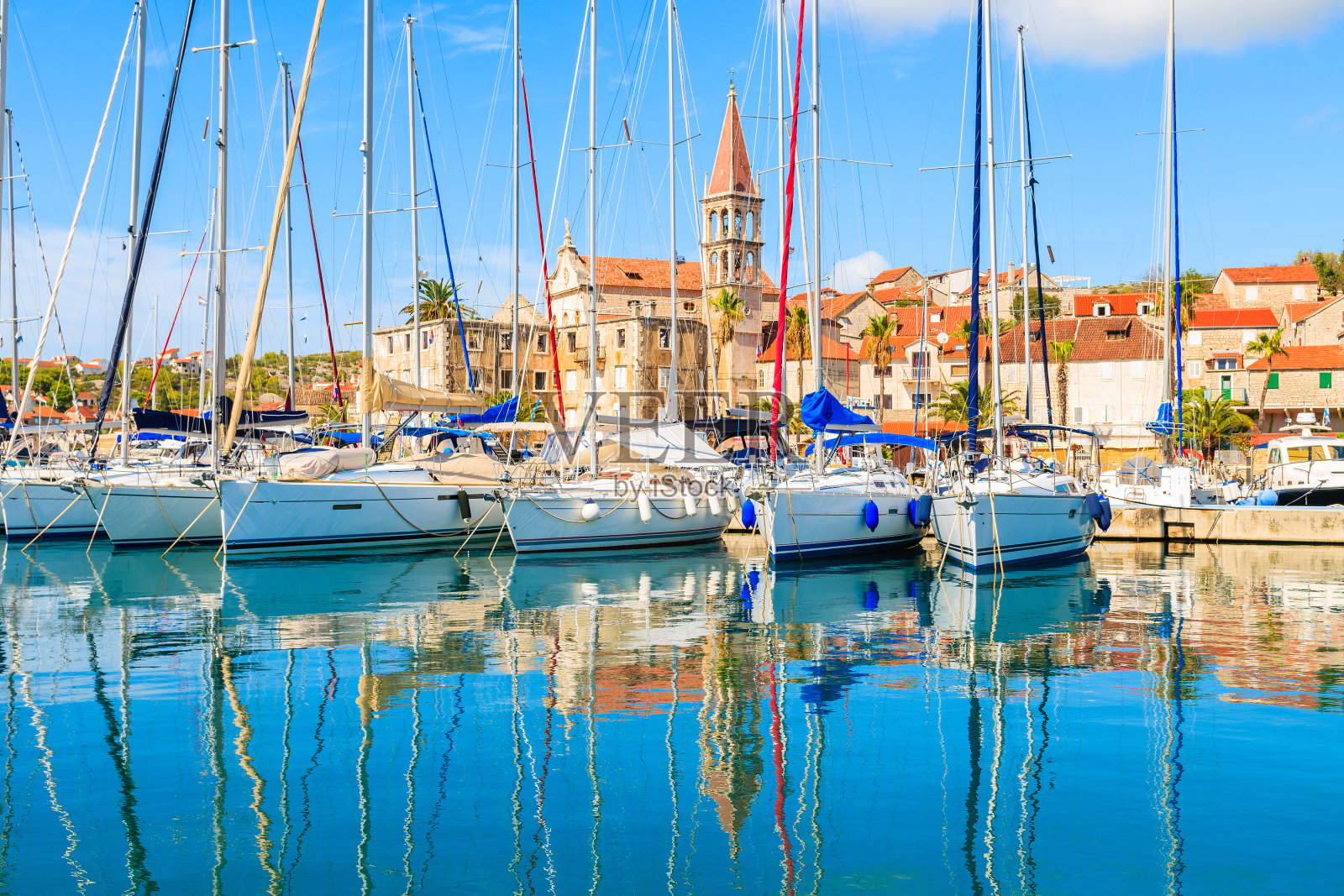 克罗地亚布拉克岛，帆船停泊在美丽的米尔纳港，背景是教堂塔照片摄影图片