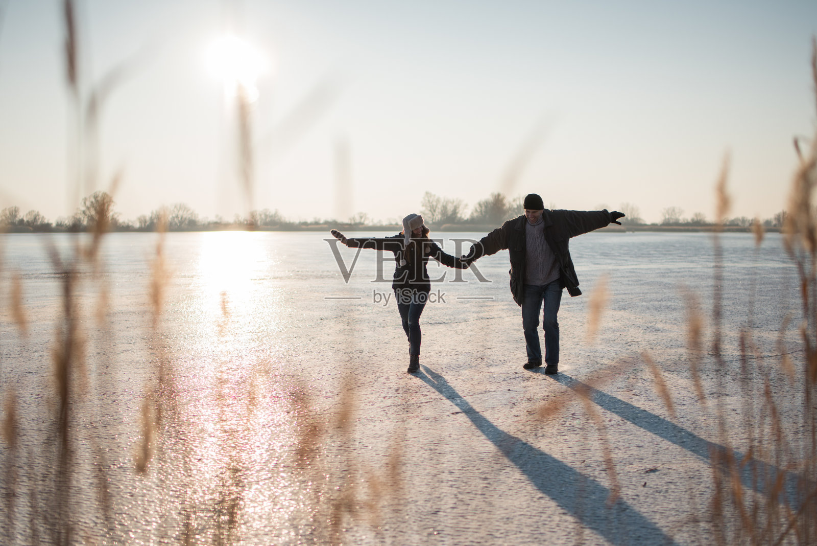 一对夫妇小心翼翼地踏在结冰的湖面上照片摄影图片