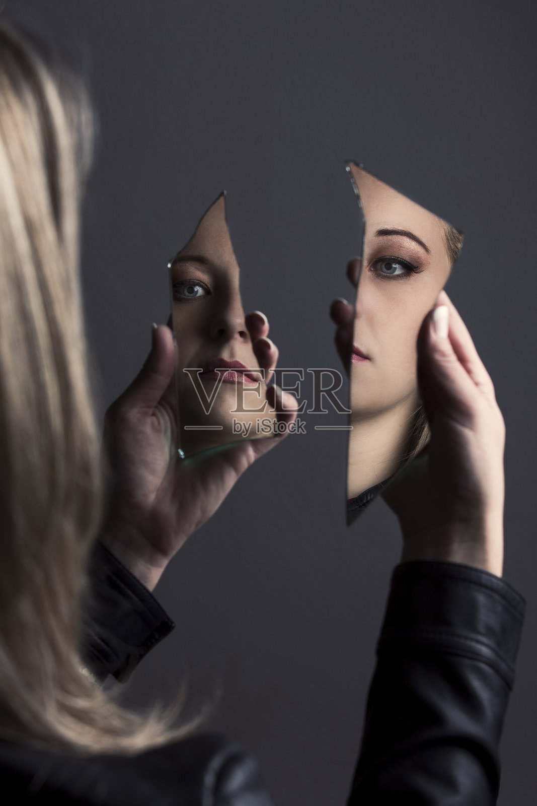 一个女人看着自己的脸在两片破碎的镜子里照片摄影图片