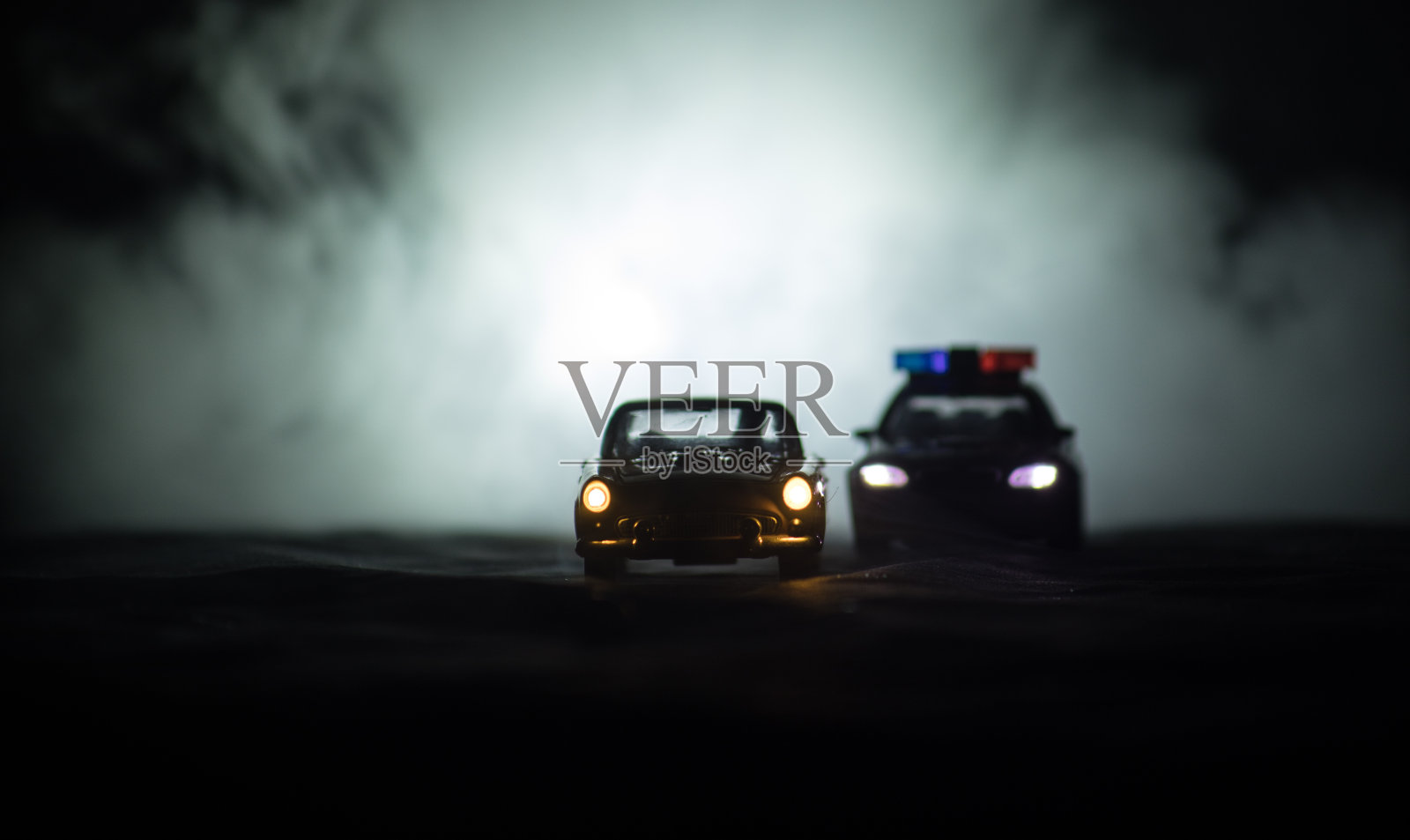 玩具宝马警车在雾背景下追赶一辆福特雷鸟车。桌上玩具装饰场景。2018年1月11日，阿塞拜疆巴库照片摄影图片
