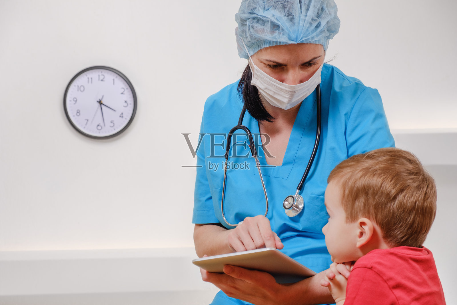 医生与听诊器和平板电脑与男孩病人在白色的背景。照片摄影图片