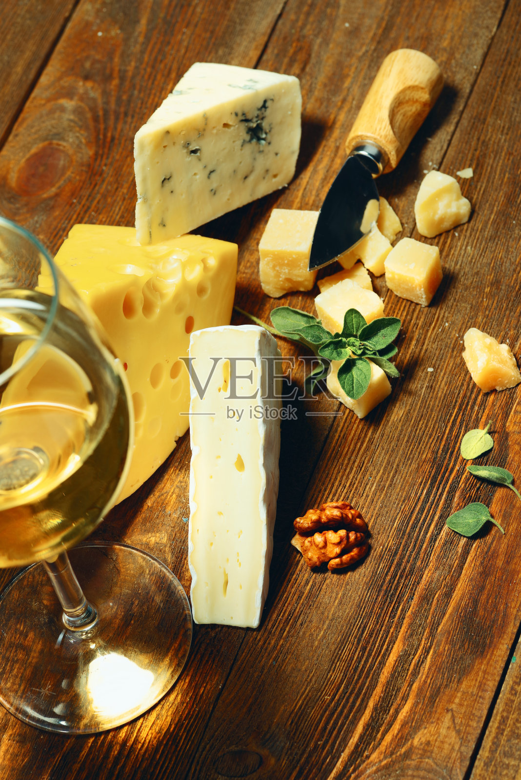 奶酪和葡萄酒装在玻璃杯里放在木板上。照片摄影图片