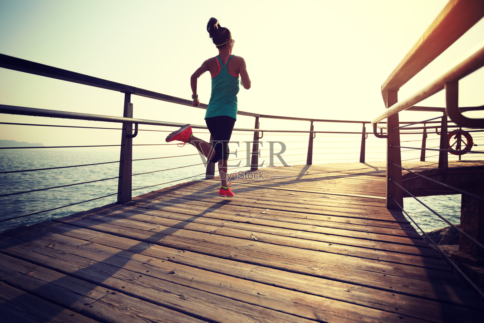 运动健身女性跑步在海滨木板路在日出照片摄影图片