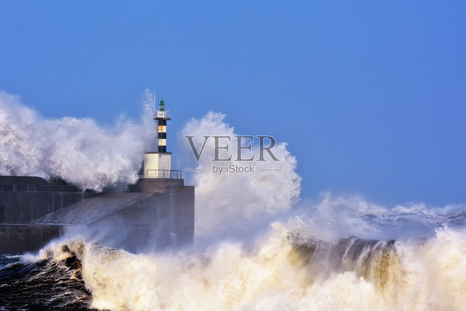 暴风雨的波浪越过灯塔和圣埃斯特班德普拉维亚码头照片摄影图片