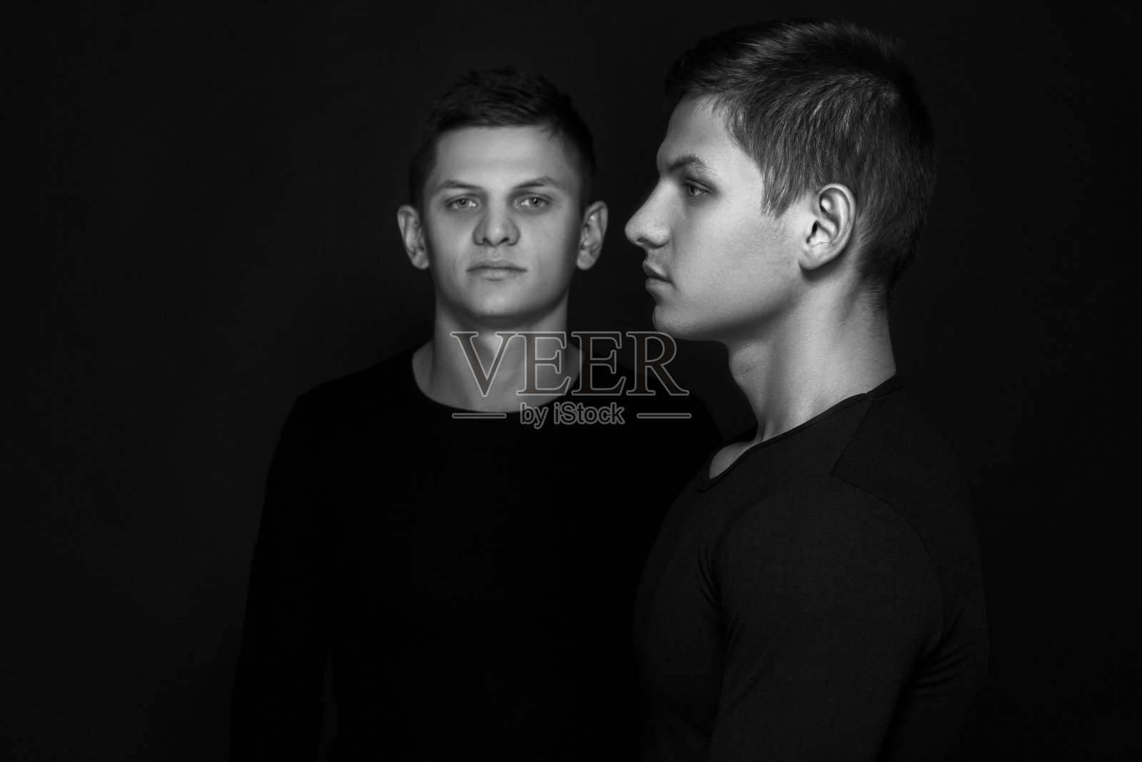 两个迷人的积极的年轻双胞胎兄弟站在穿着照片摄影图片