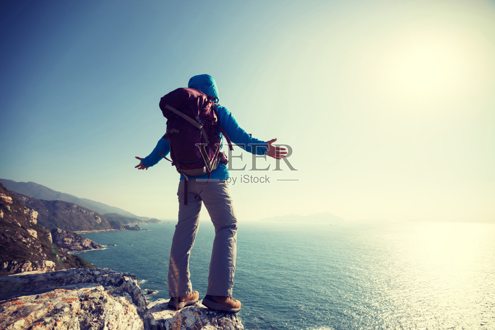 成功的女性徒步者站在日出海边山崖边照片摄影图片