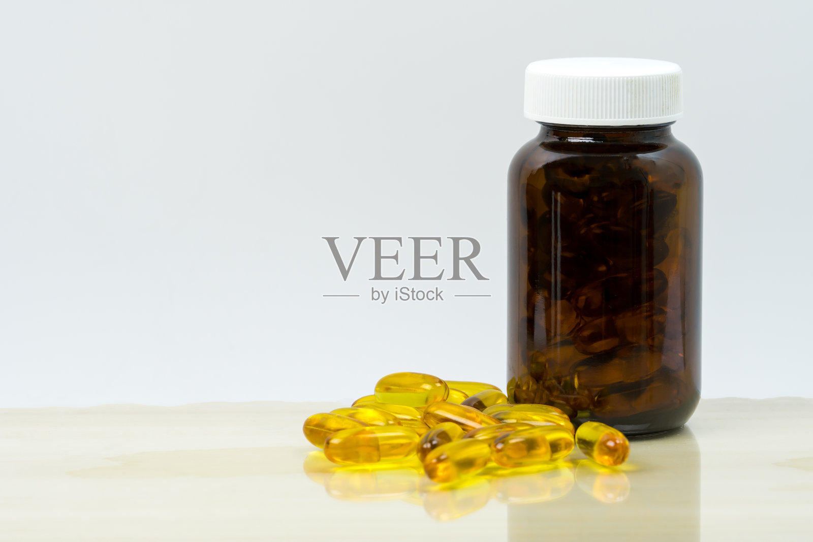 黄色鱼油胶囊，琥珀色玻璃瓶，空白标签，桌子上有文字拷贝空间。心脏和关节保健的维生素和补品。omega - 3, EPA和DHA的来源。照片摄影图片