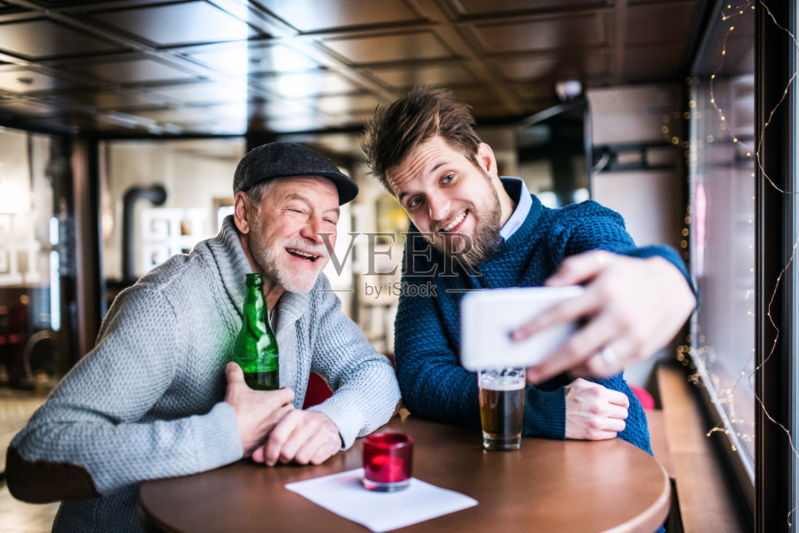 老父亲和小儿子在酒吧里玩智能手机。照片摄影图片