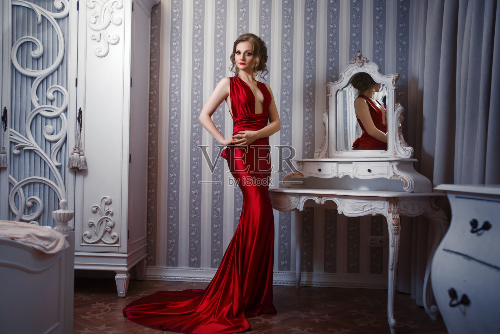 一个优雅苗条的女人穿着一件红色的连衣裙，内饰别致。照片摄影图片