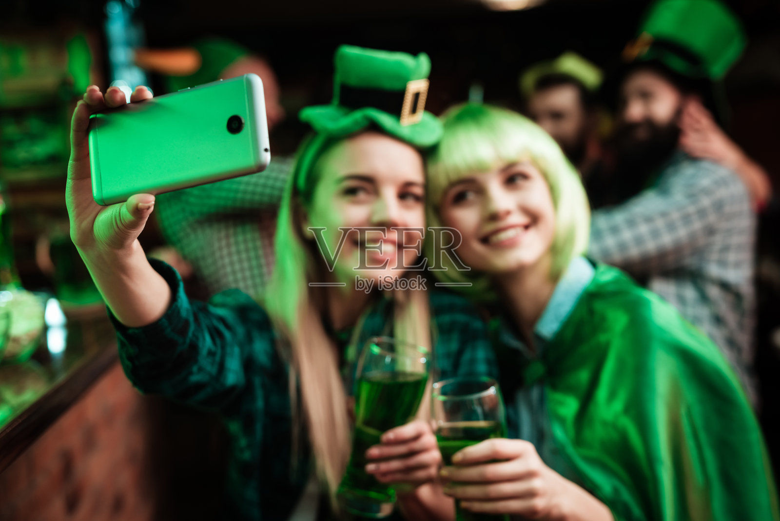 两个戴着假发和帽子的女孩在酒吧里自拍。照片摄影图片