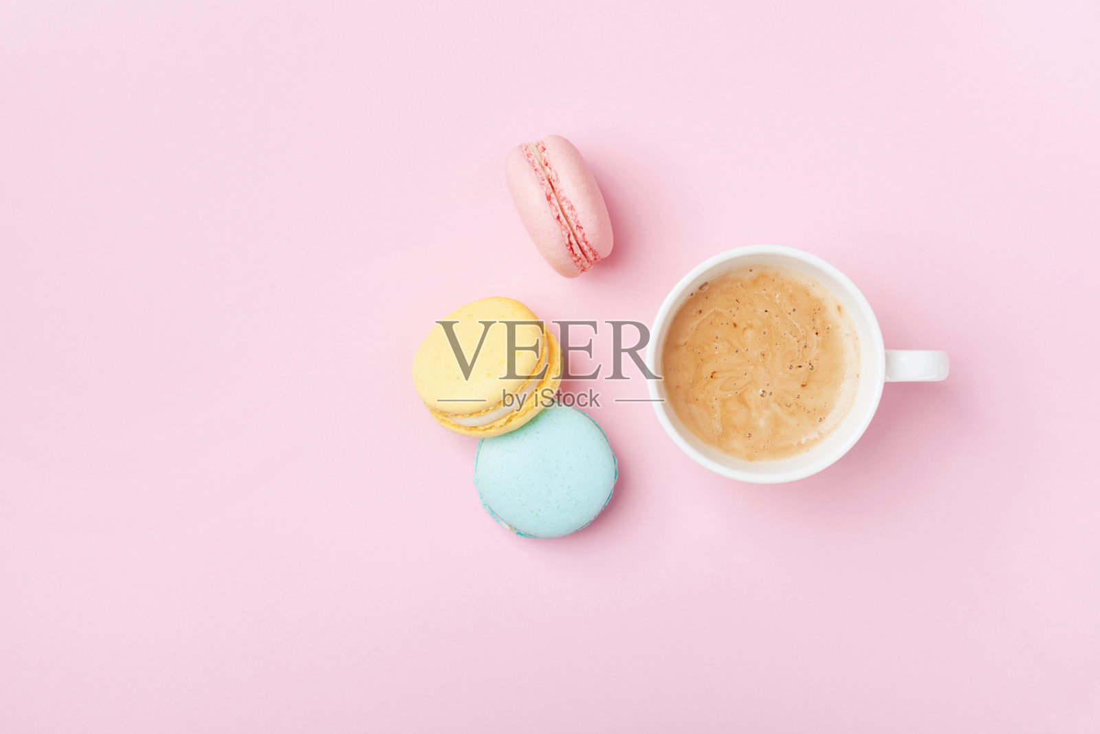 一杯咖啡和彩色马卡龙在淡粉色的背景俯视图。温馨的早餐。时尚公寓。照片摄影图片