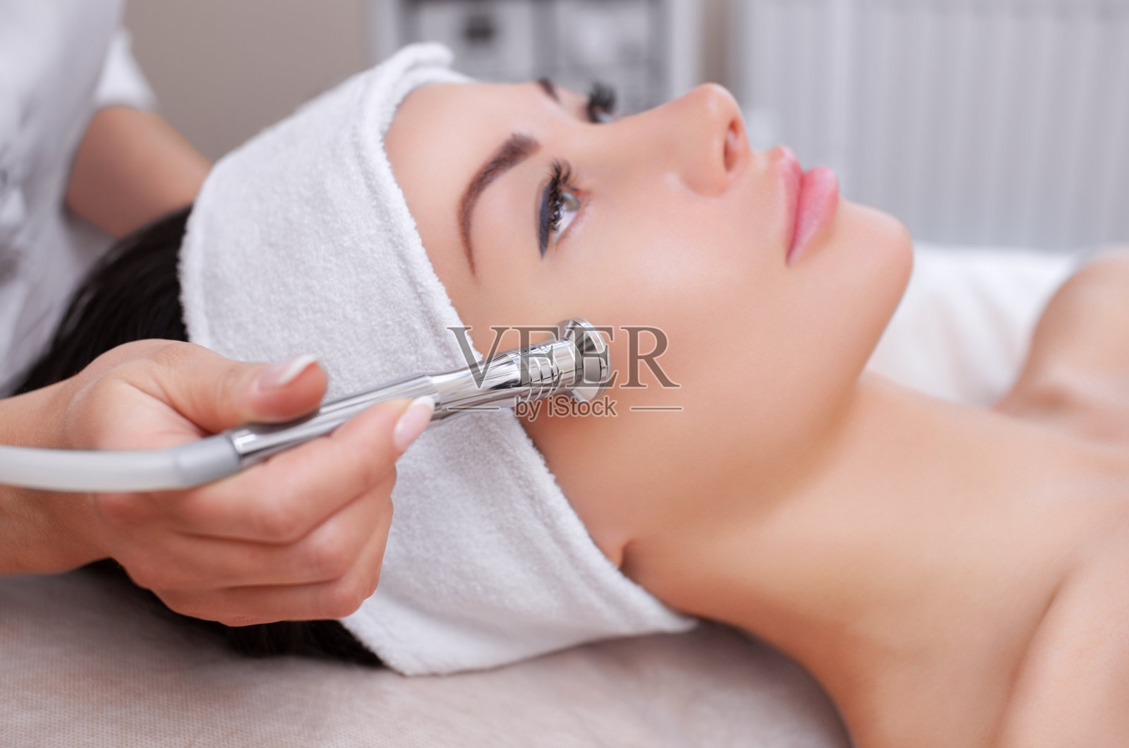 美容师用微晶换肤术给一位美丽年轻的女士做面部皮肤照片摄影图片