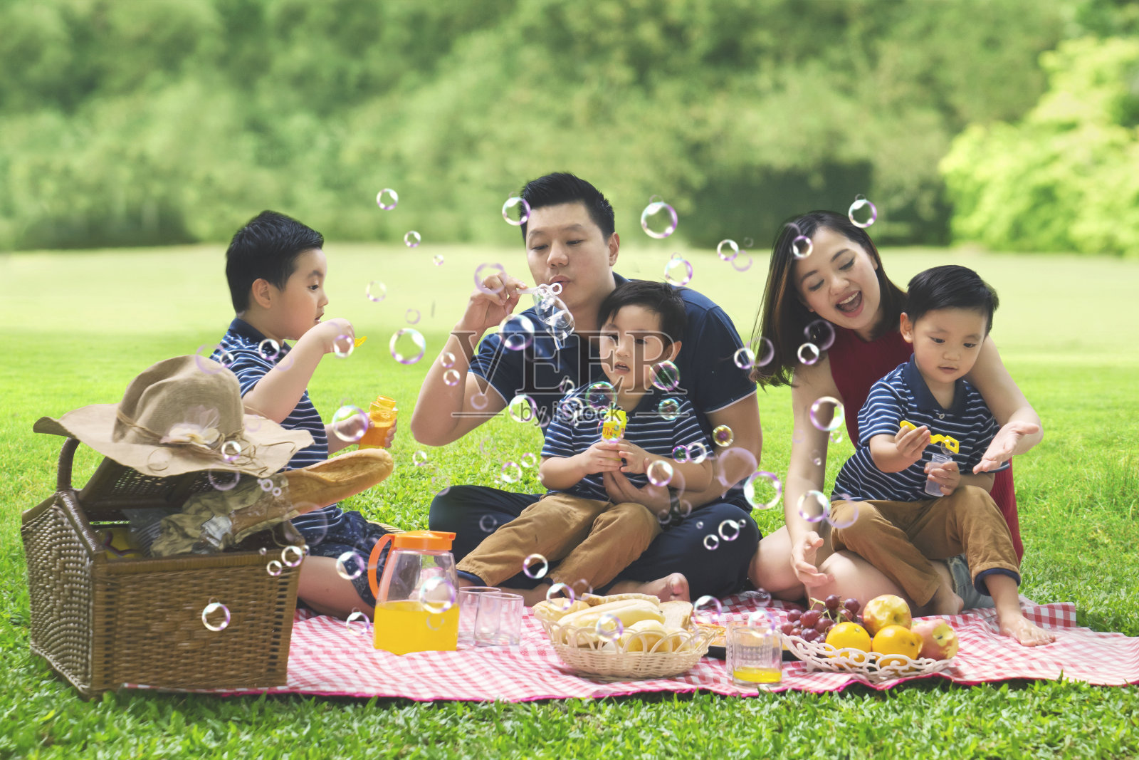 亚洲家庭在公园里吹肥皂泡照片摄影图片