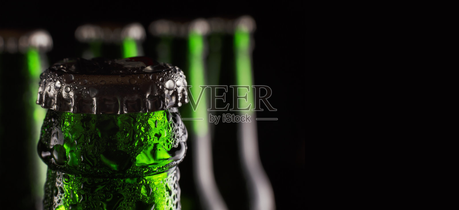 St.Patrick的一天。新鲜的绿色啤酒在瓶中与冷凝液滴在黑色背景。概念:酒吧，庆祝圣帕特里克节照片摄影图片