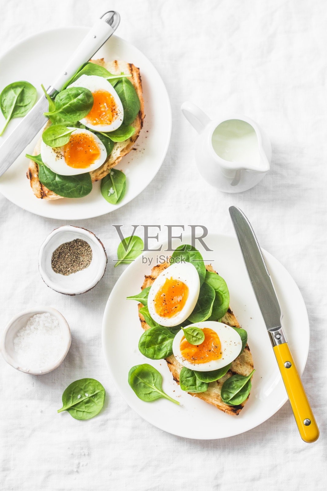 提供复活节早午餐盘子-烤面包三明治与菠菜和煮鸡蛋在白色的背景，俯视图照片摄影图片