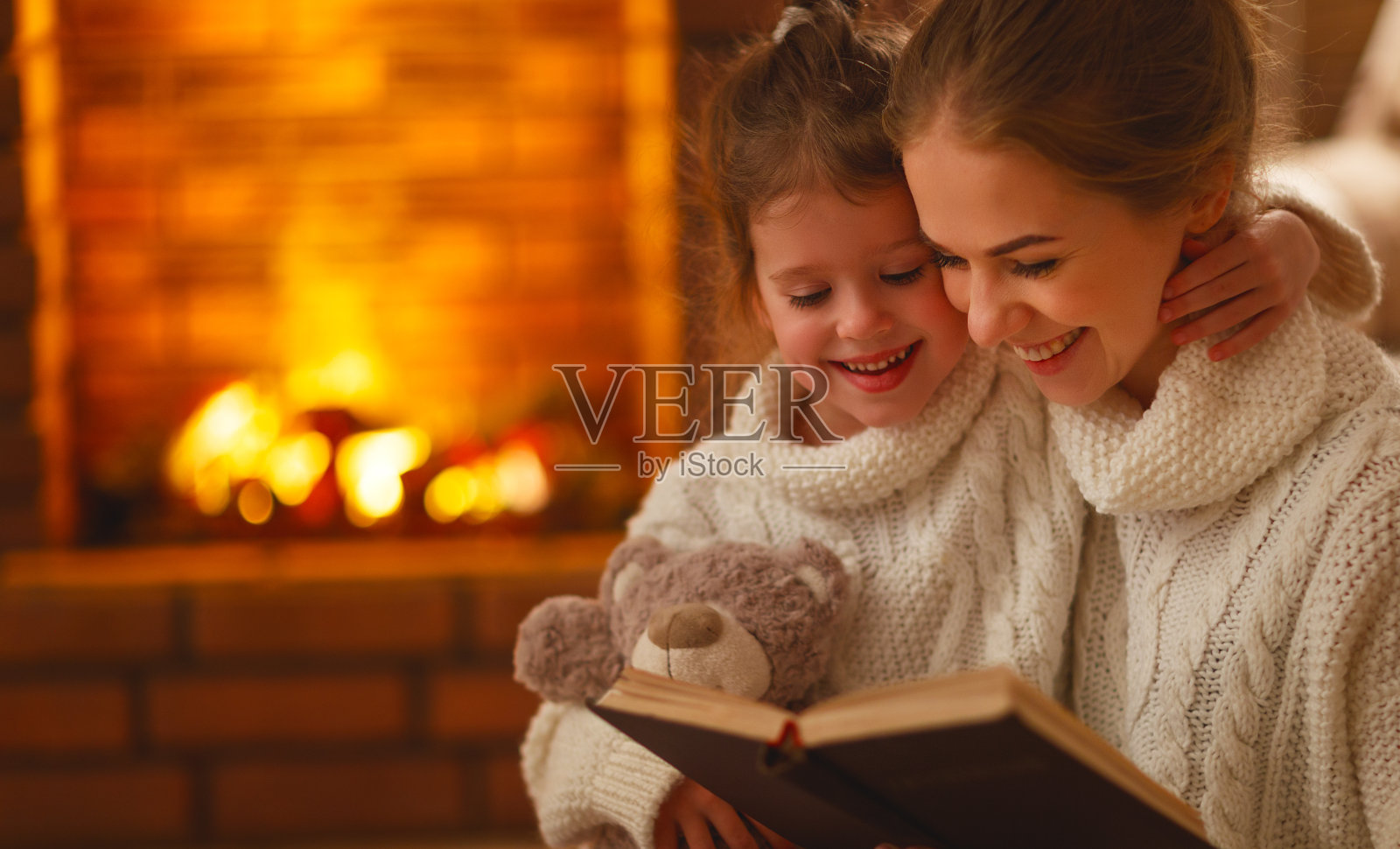 幸福的家庭妈妈和孩子女儿在冬天的晚上看书照片摄影图片