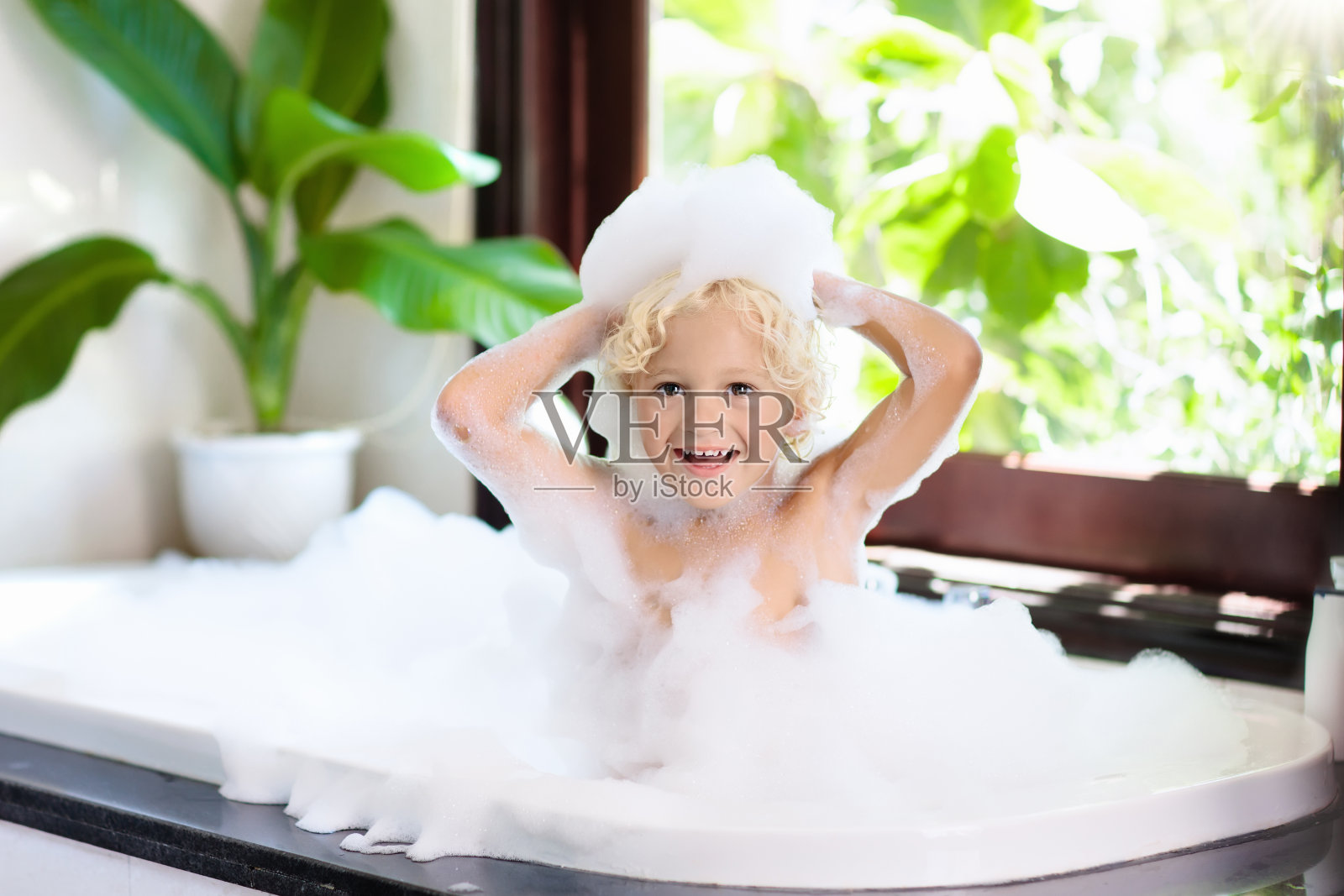 泡泡浴中的孩子。孩子洗澡。婴儿淋浴。照片摄影图片