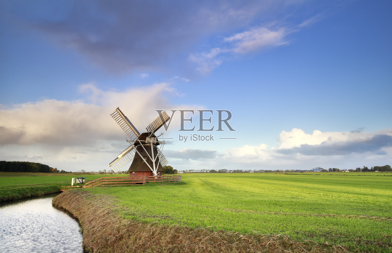 荷兰河边绿色草地上的荷兰风车照片摄影图片
