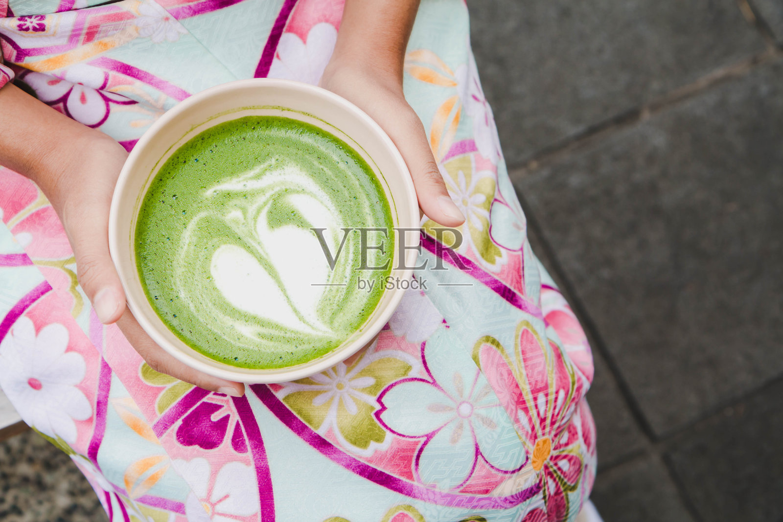 一个穿着漂亮和服的女人手里拿着一杯抹茶拿铁绿茶。日本本土饮品的概念。照片摄影图片