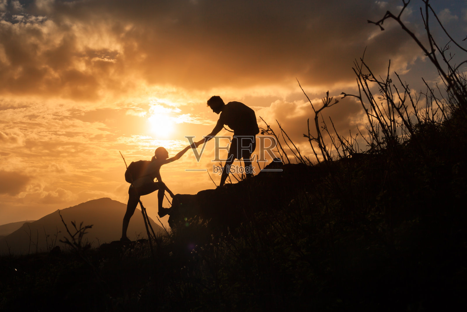 日出时，人们互相帮助爬山。照片摄影图片