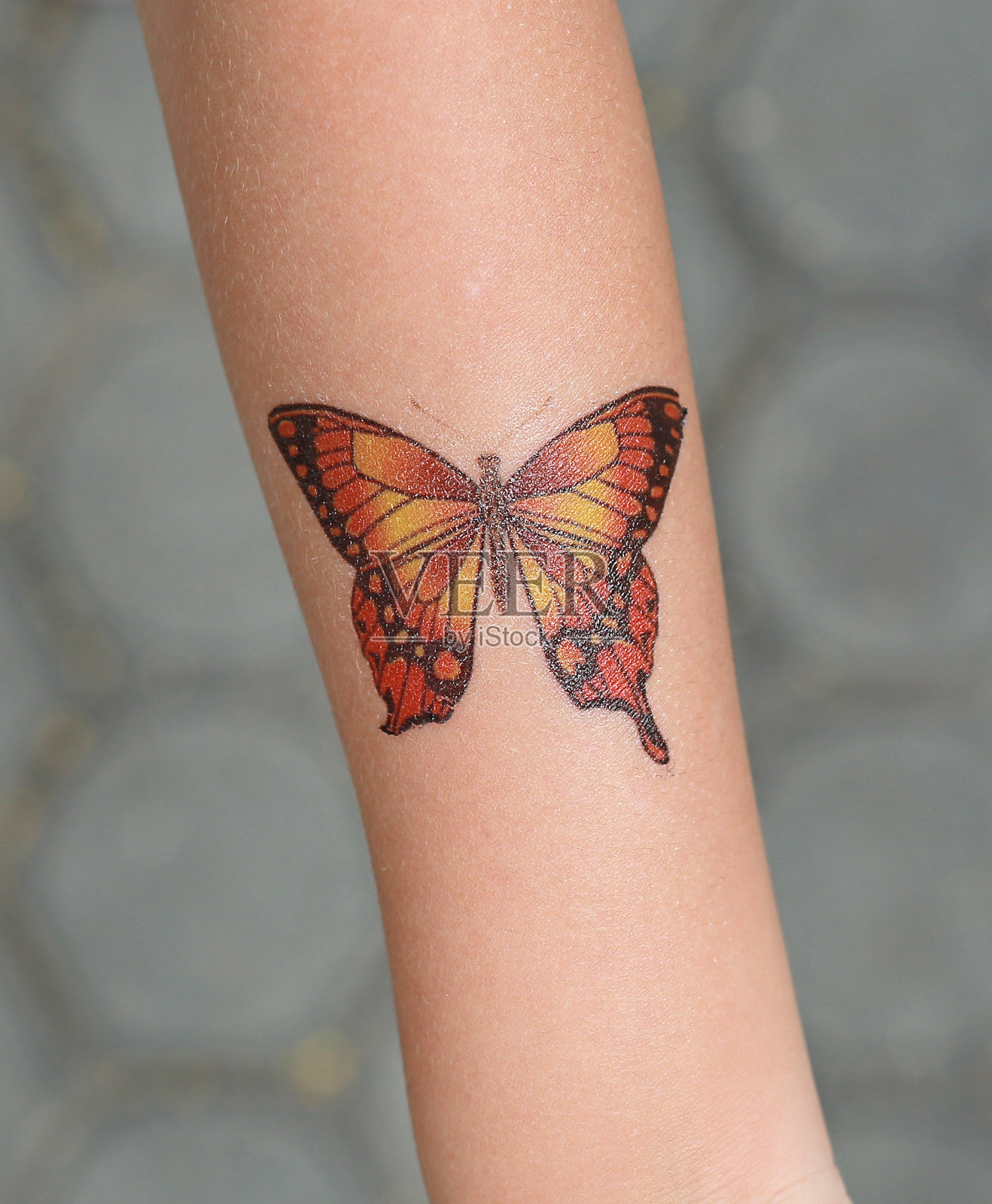 蝴蝶贴纸在孩子的手上，装扮纹身。照片摄影图片