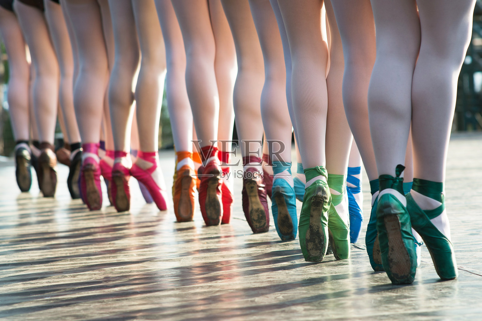 在一场表演中，芭蕾舞者的脚穿着几种颜色的芭蕾舞鞋在舞台上跳舞。照片摄影图片