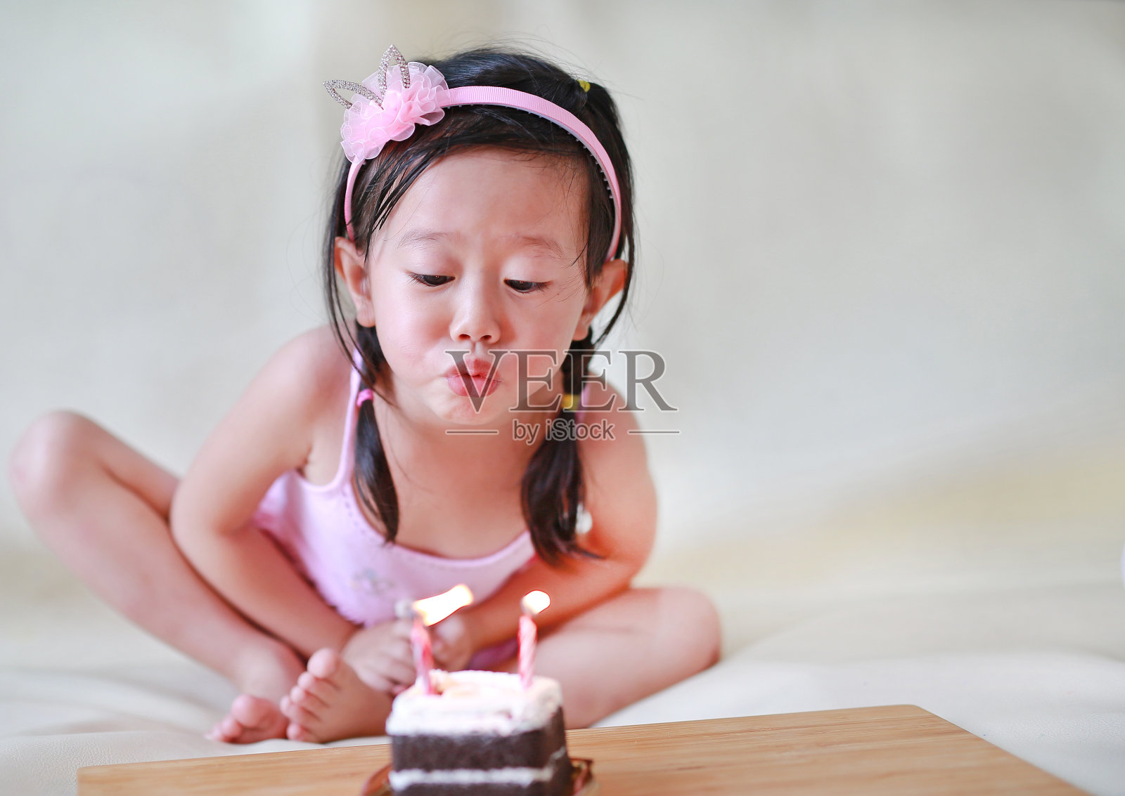 可爱的小女孩吹着小生日蜡烛，庆祝2岁的孩子。照片摄影图片