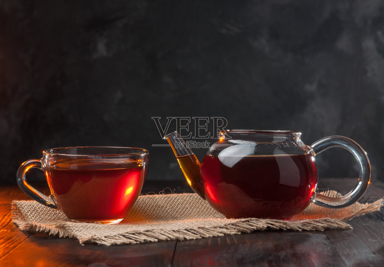 茶道，一杯刚泡好的红茶和一个玻璃茶壶，光线温暖柔和，背景较暗。照片摄影图片